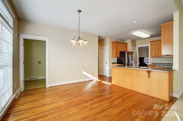 kitchen with sink, a wealth of natural light, stainless steel fridge with ice dispenser, a breakfast bar area, and a chandelier