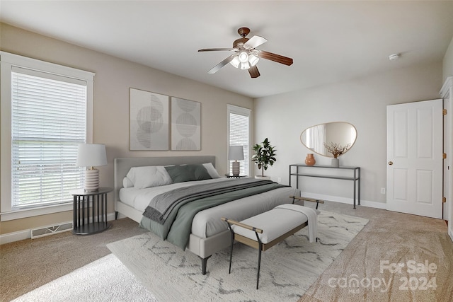 carpeted bedroom featuring multiple windows and ceiling fan