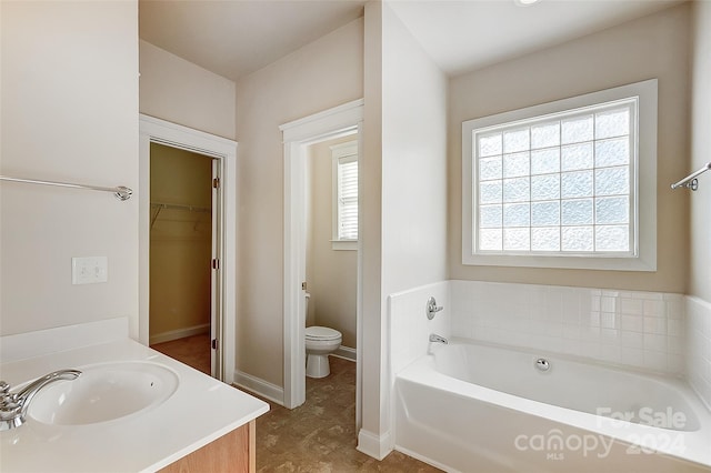 bathroom featuring a washtub, vanity, and toilet