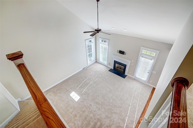 unfurnished living room featuring a wealth of natural light, ceiling fan, light carpet, and high vaulted ceiling