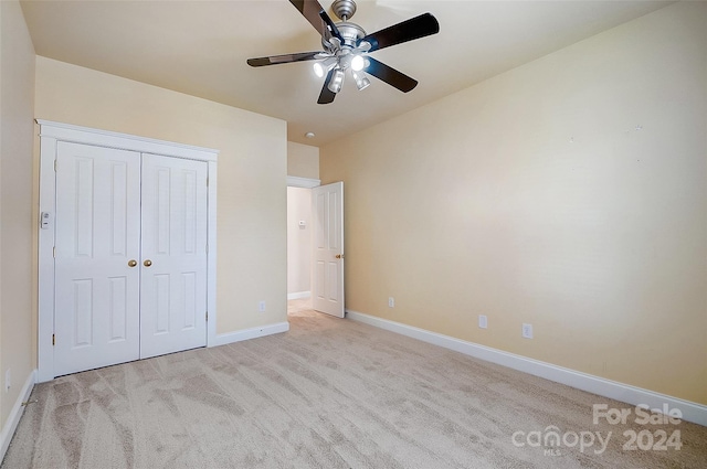 unfurnished bedroom with light carpet, a closet, and ceiling fan