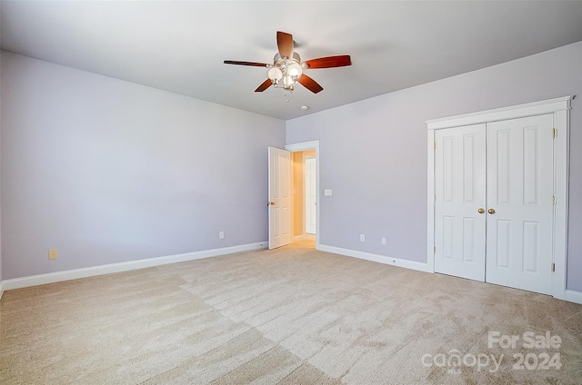 unfurnished bedroom with ceiling fan, a closet, and light carpet