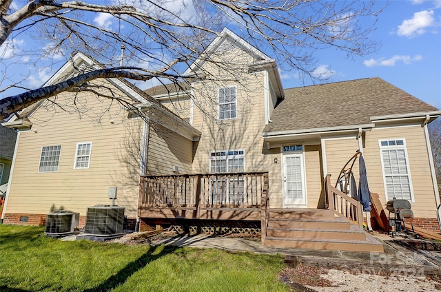 rear view of house featuring central air condition unit, a wooden deck, and a lawn