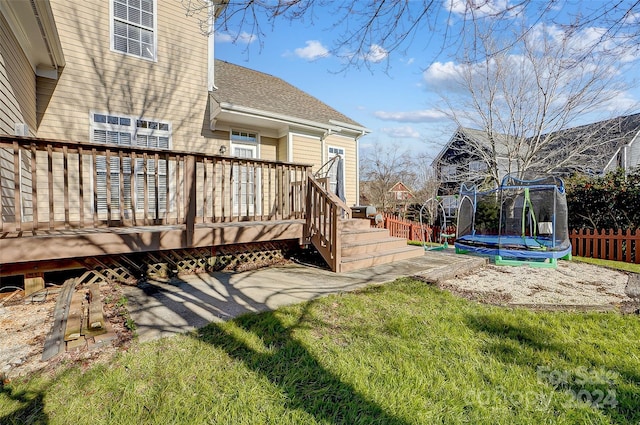 view of yard with a trampoline and a wooden deck