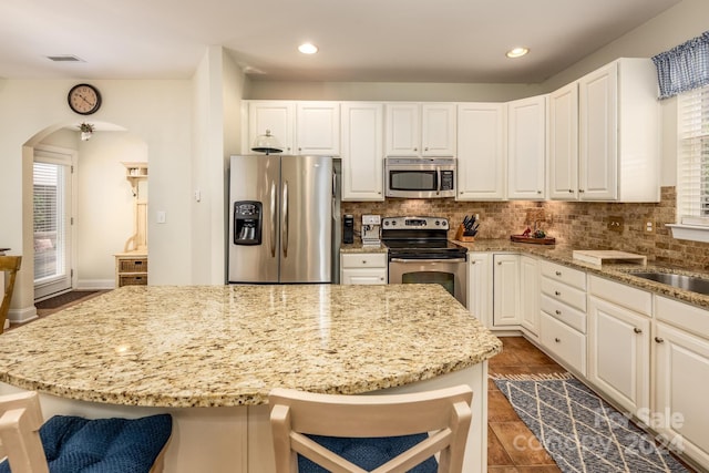 kitchen featuring a breakfast bar, stainless steel appliances, and light stone counters