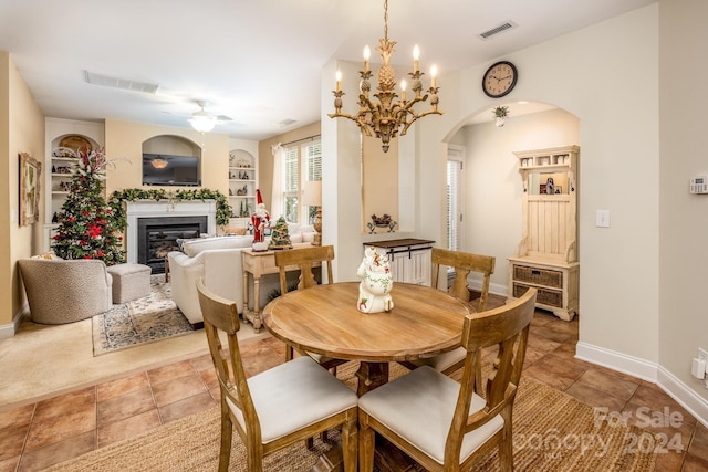 tiled dining area featuring ceiling fan with notable chandelier and built in features