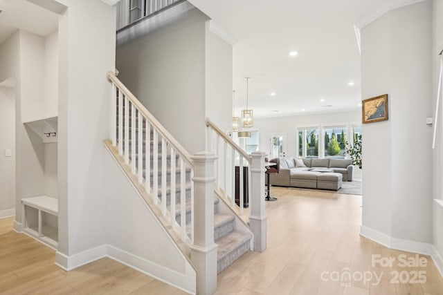 stairs with hardwood / wood-style floors and ornamental molding