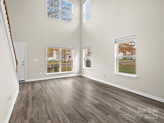 unfurnished living room with a towering ceiling and dark hardwood / wood-style floors