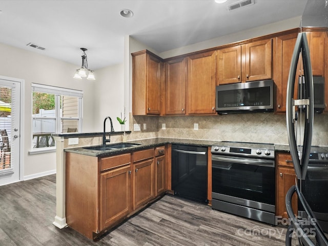 kitchen featuring sink, kitchen peninsula, hanging light fixtures, dark hardwood / wood-style floors, and black appliances