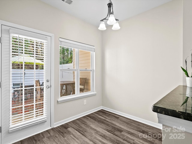 unfurnished dining area with a notable chandelier and dark hardwood / wood-style floors