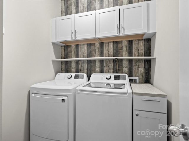 clothes washing area with cabinets and washing machine and clothes dryer