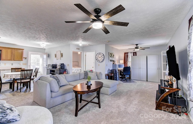 carpeted living room featuring ceiling fan and a textured ceiling