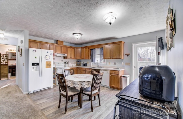 kitchen with a textured ceiling, sink, light hardwood / wood-style floors, and white appliances