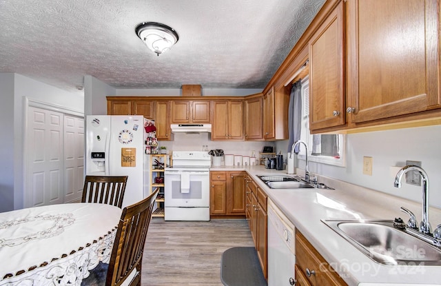 kitchen featuring a textured ceiling, light hardwood / wood-style floors, white appliances, and sink