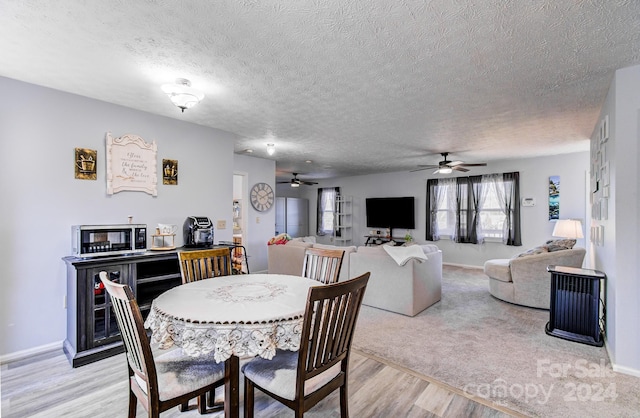 dining area featuring a textured ceiling, light wood-type flooring, and ceiling fan