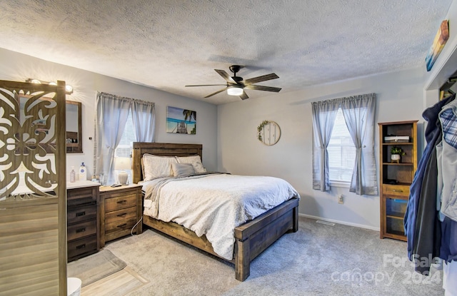 carpeted bedroom with ceiling fan, a textured ceiling, and multiple windows