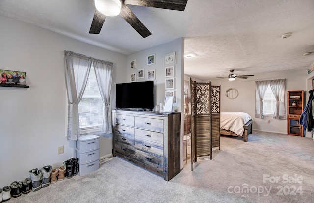 carpeted bedroom featuring ceiling fan and a textured ceiling