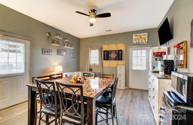 dining space with light hardwood / wood-style floors and ceiling fan