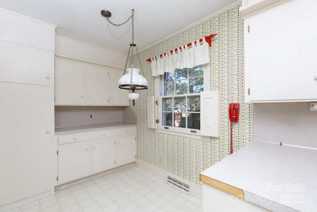 kitchen featuring decorative light fixtures, white cabinetry, and ornamental molding