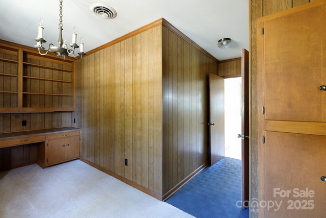 unfurnished office featuring wood walls, light colored carpet, and an inviting chandelier