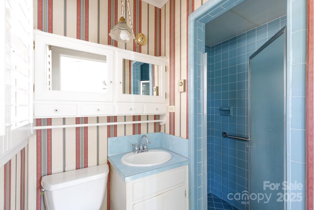 bathroom with tiled shower, vanity, and toilet