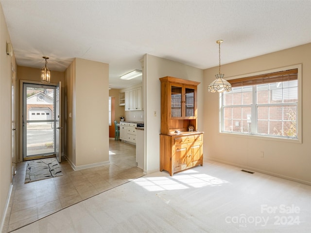 unfurnished dining area with a textured ceiling, light colored carpet, and a wealth of natural light