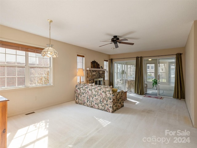 unfurnished living room with a fireplace, light colored carpet, and ceiling fan