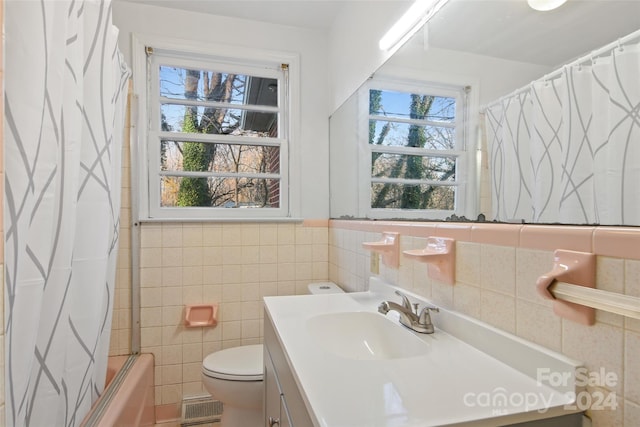 full bathroom with vanity, shower / bathtub combination with curtain, tile walls, and a healthy amount of sunlight