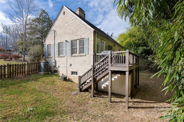 rear view of property with a lawn, a wooden deck, and central AC