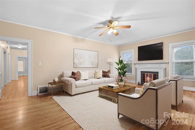 living room featuring light hardwood / wood-style floors, crown molding, and a healthy amount of sunlight