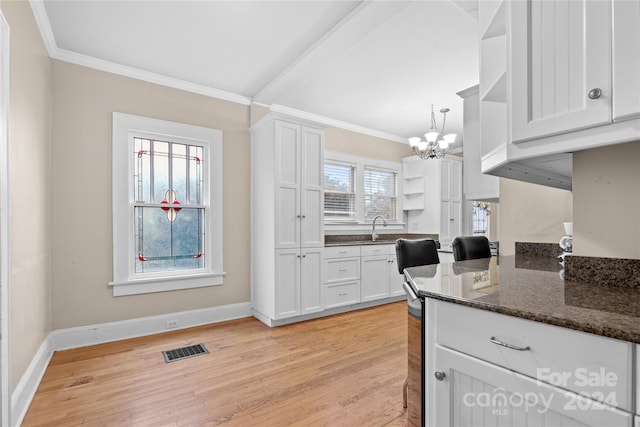 kitchen featuring dark stone counters, white cabinets, light hardwood / wood-style floors, and ornamental molding