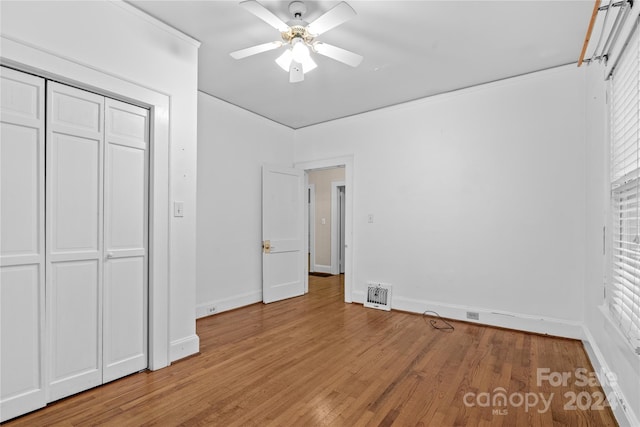 unfurnished bedroom featuring hardwood / wood-style flooring, ceiling fan, and a closet