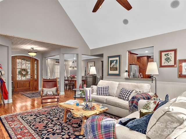 living room with ceiling fan, high vaulted ceiling, and light hardwood / wood-style flooring