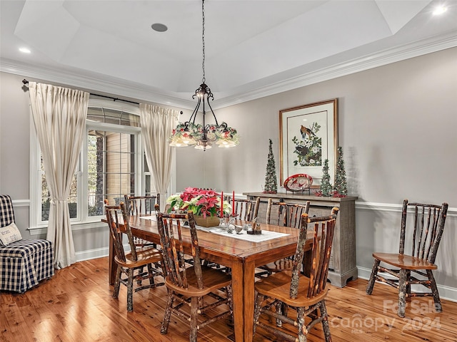 dining room with an inviting chandelier, a tray ceiling, light hardwood / wood-style flooring, and crown molding