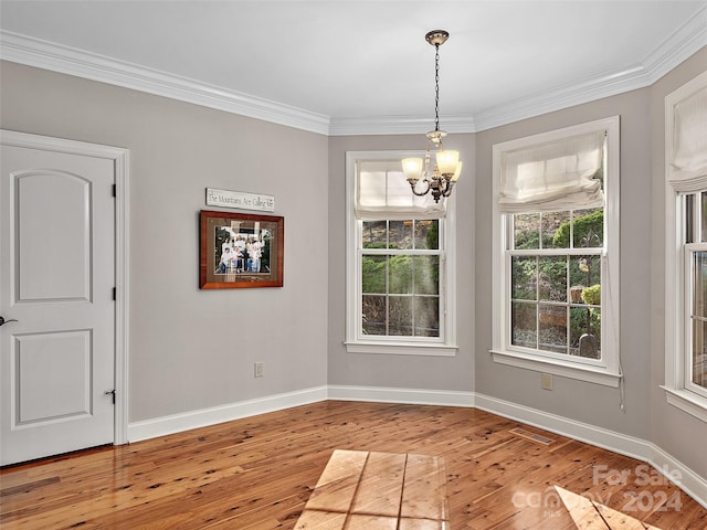 unfurnished dining area with a notable chandelier, crown molding, and light hardwood / wood-style flooring