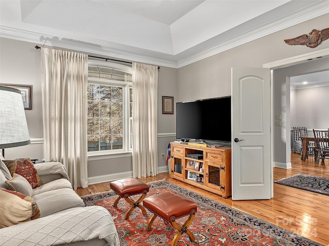 living room featuring a raised ceiling, hardwood / wood-style floors, and ornamental molding