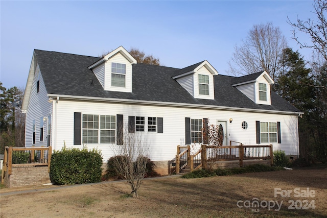 cape cod house featuring a front yard and a deck