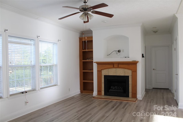 unfurnished living room with light hardwood / wood-style floors, ornamental molding, a fireplace, and a wealth of natural light