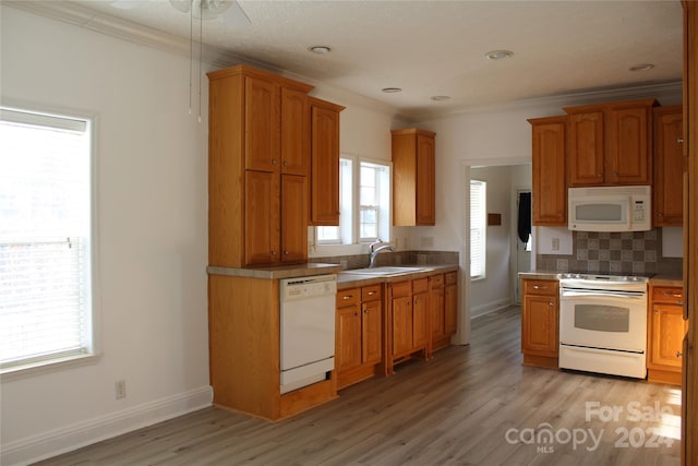 kitchen with white appliances, crown molding, sink, tasteful backsplash, and light hardwood / wood-style floors