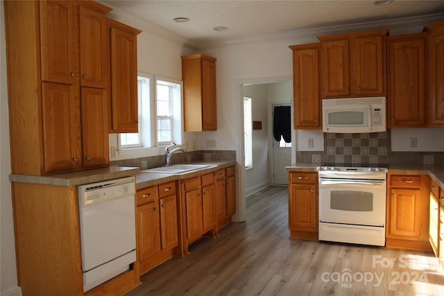 kitchen featuring decorative backsplash, ornamental molding, white appliances, sink, and light hardwood / wood-style floors