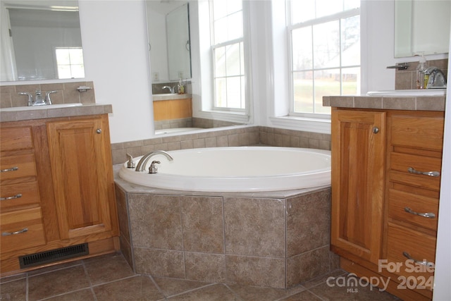 bathroom with tile patterned flooring, vanity, and tiled tub