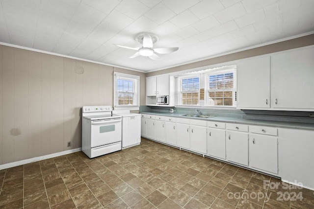 kitchen with ceiling fan, sink, electric stove, white cabinetry, and wood walls