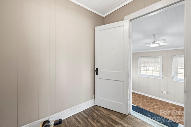 empty room featuring wooden walls, crown molding, ceiling fan, and dark hardwood / wood-style floors