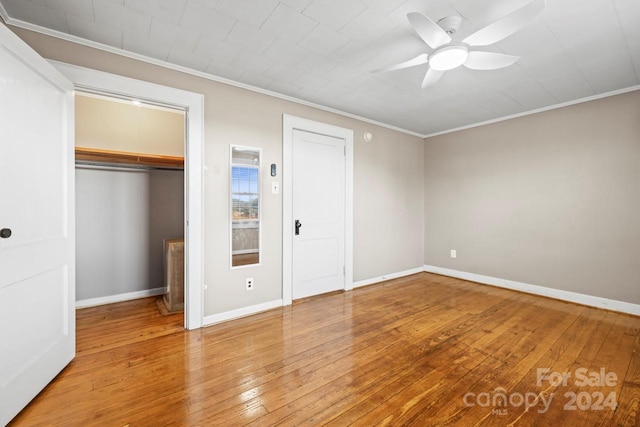 unfurnished bedroom featuring hardwood / wood-style floors, ceiling fan, crown molding, and a closet