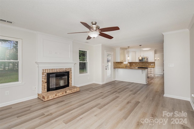 unfurnished living room featuring a fireplace, light hardwood / wood-style flooring, and a textured ceiling