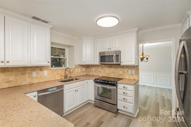 kitchen with sink, stainless steel appliances, light hardwood / wood-style floors, white cabinets, and ornamental molding