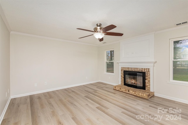 unfurnished living room with a textured ceiling, light hardwood / wood-style floors, a brick fireplace, and ornamental molding