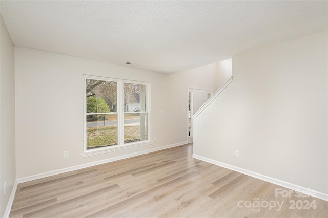 unfurnished room with a textured ceiling and light hardwood / wood-style flooring