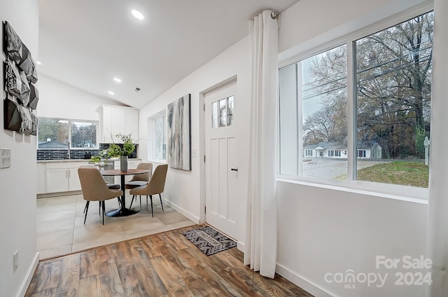 dining area with a wealth of natural light, light hardwood / wood-style floors, and lofted ceiling