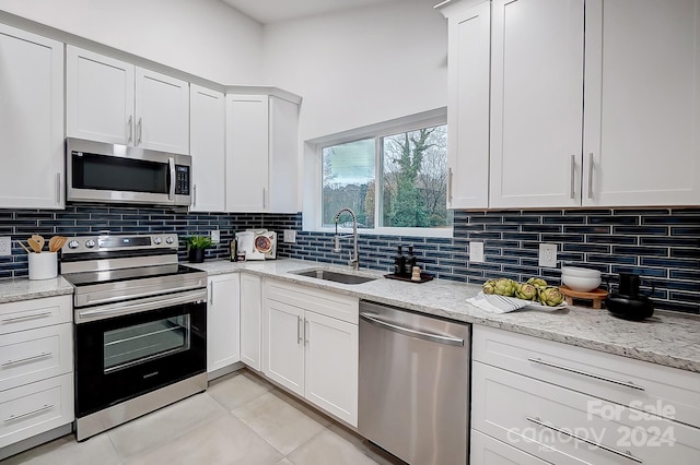 kitchen featuring decorative backsplash, sink, white cabinets, and appliances with stainless steel finishes